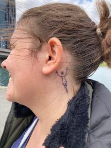 Das Tattoo hinter Veronikas Ohr zeigt eine weibliche Figur mit Sternkopf.